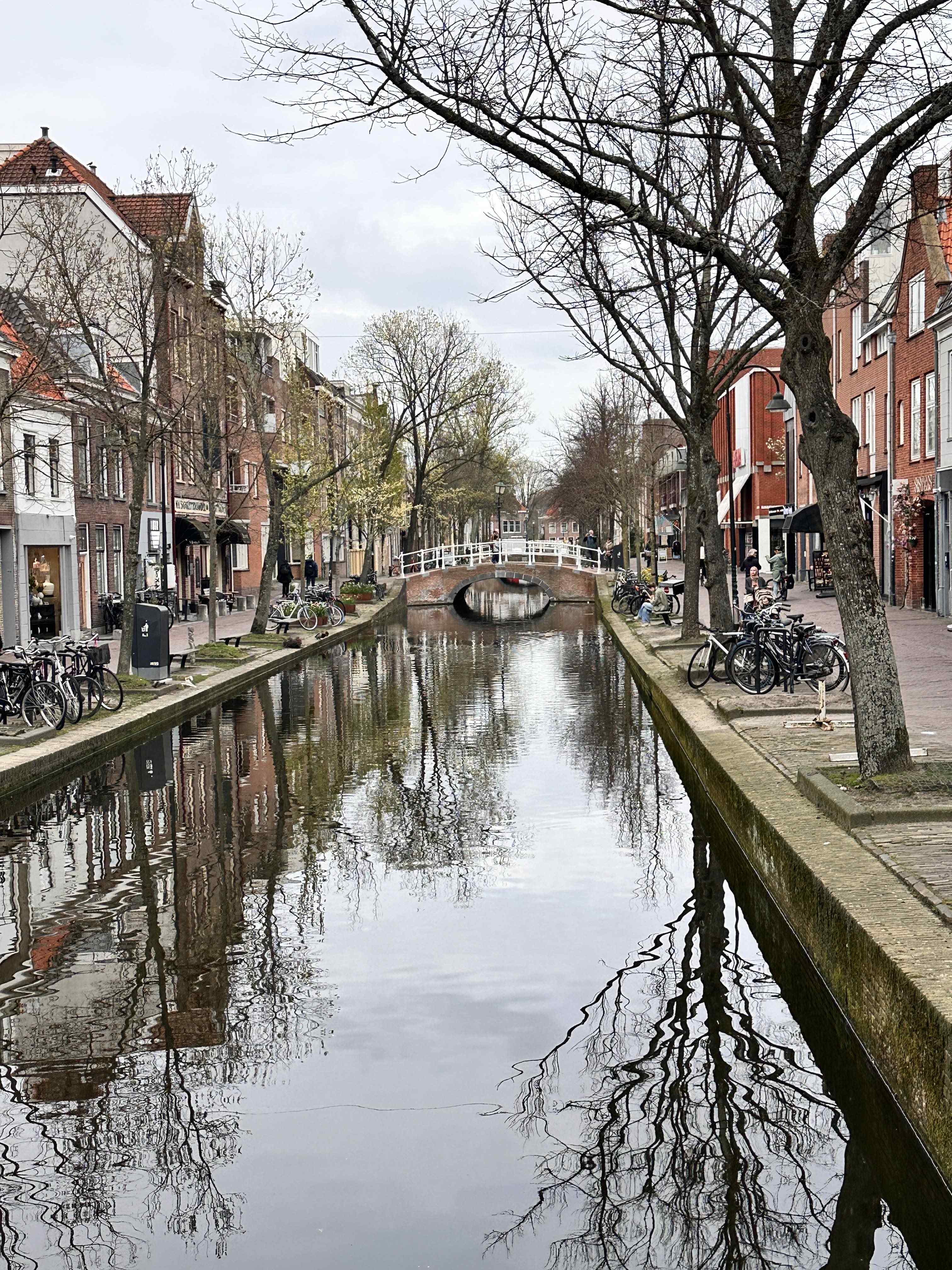 A canal street in Delft with bicycles and historic buildings