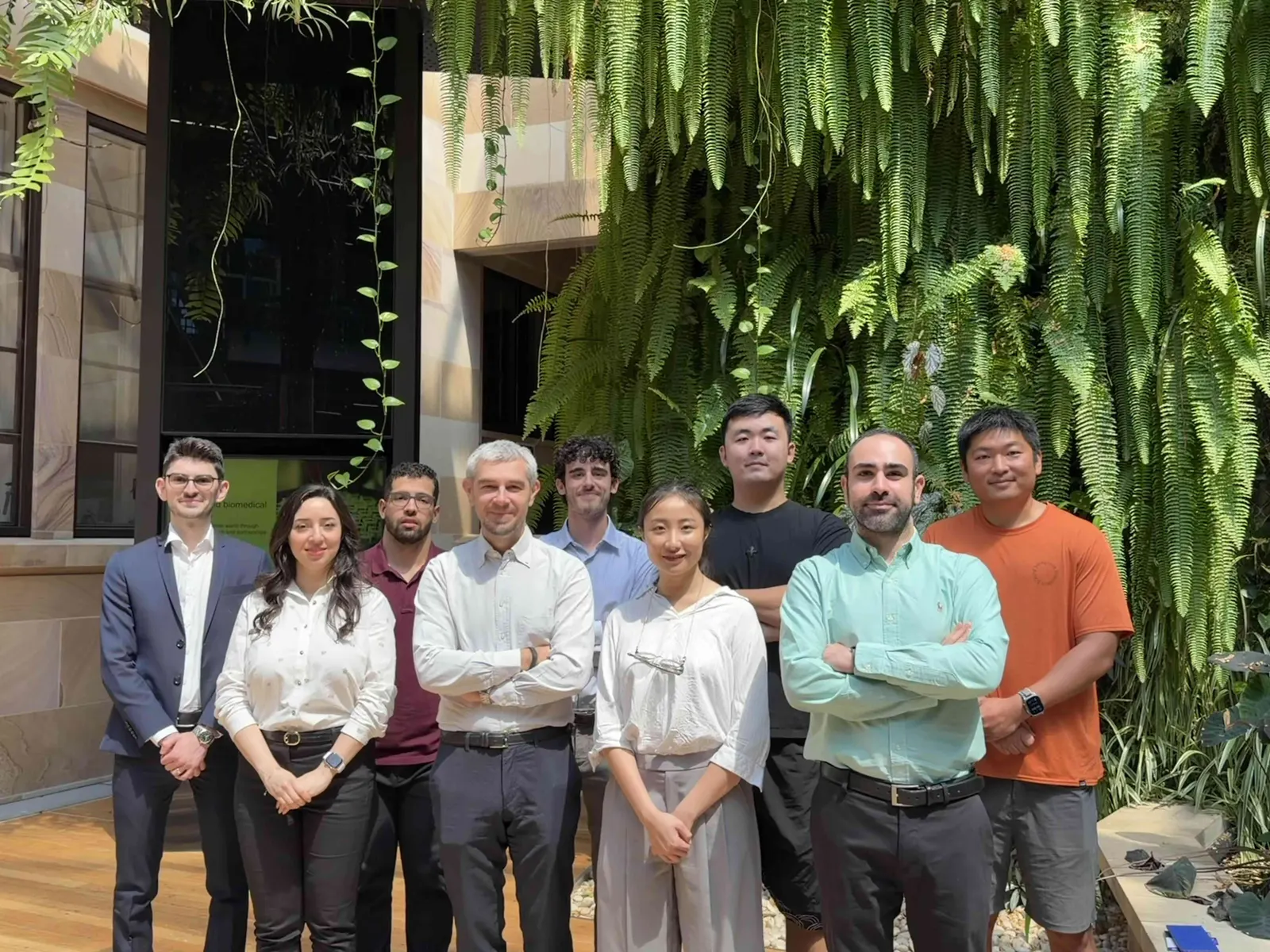 DLab members standing in front of a green wall in a campus courtyard
