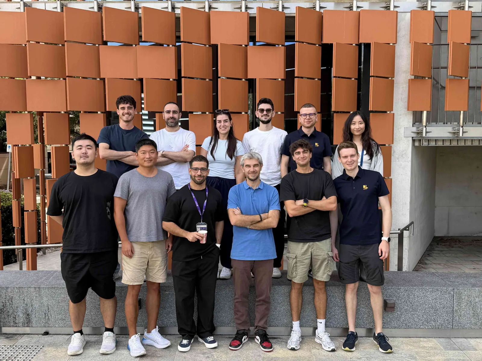 DLab members in front of an orange sculptural wall on campus