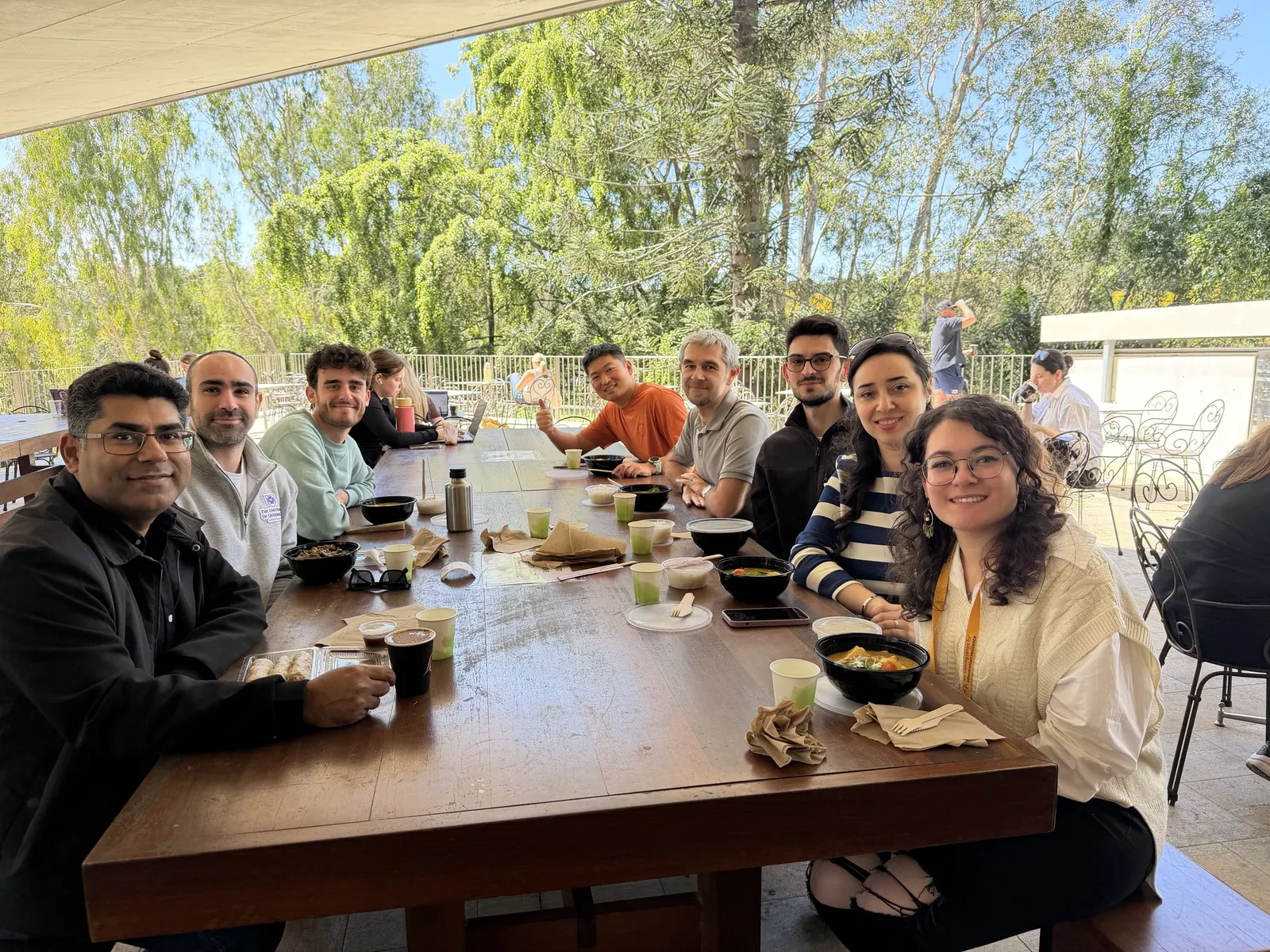 DLab members at a long lunch table under a covered terrace