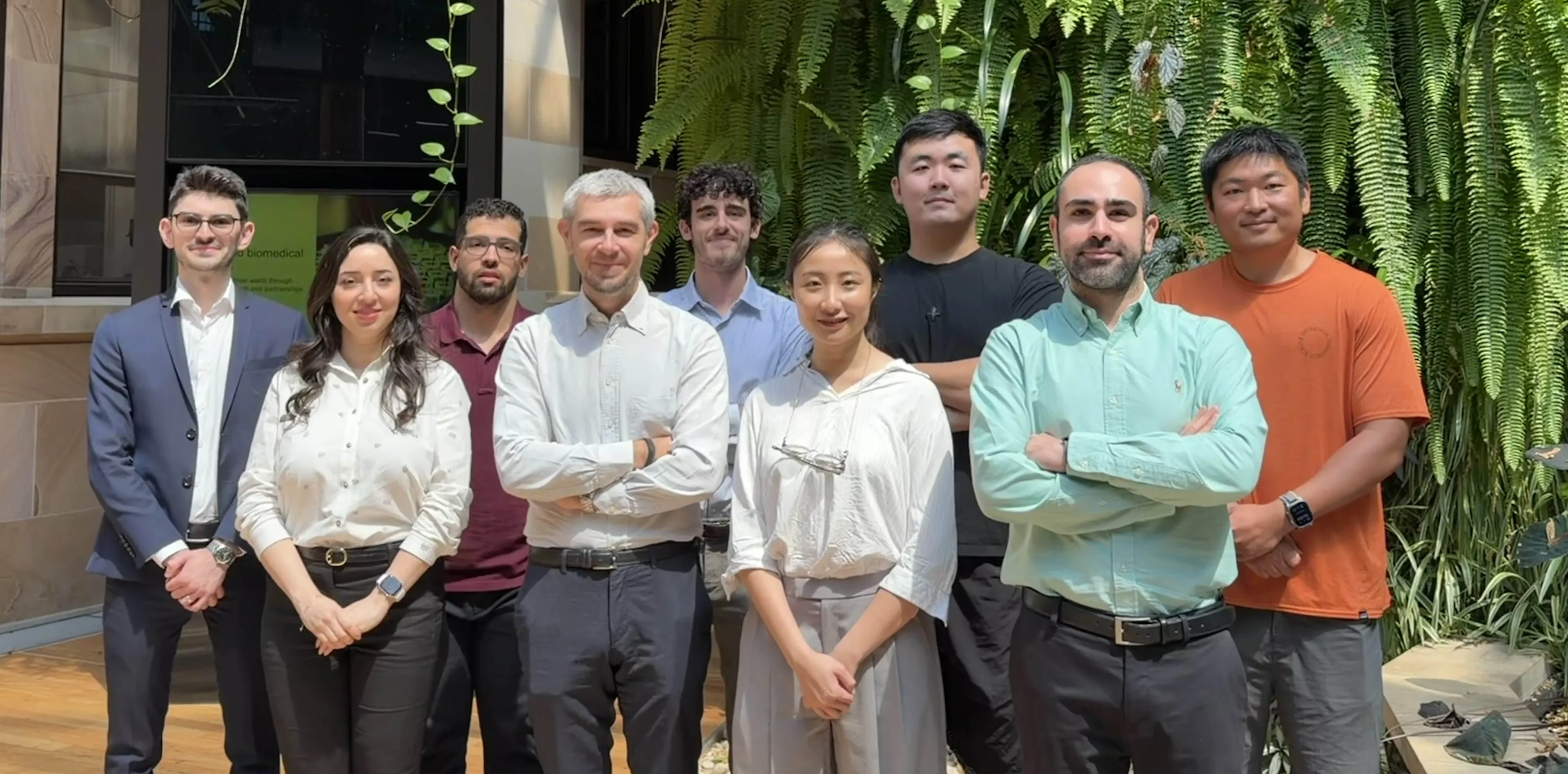 DLab members standing together in front of a green wall at The University of Queensland