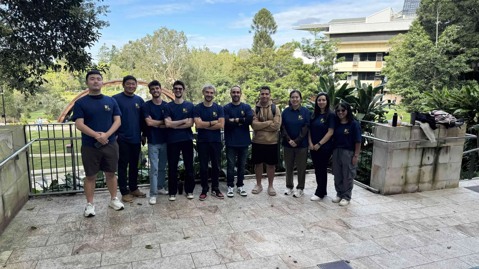 DLab members in lab shirts on a campus terrace surrounded by trees