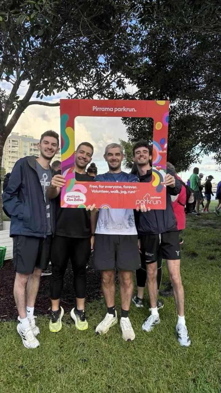 Lab members holding a parkrun photo frame in a park